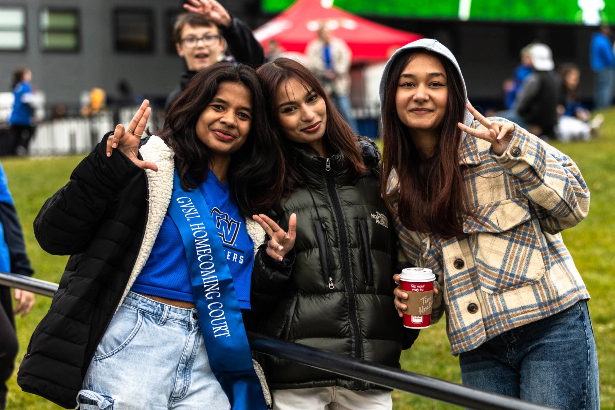 three students pose at football game